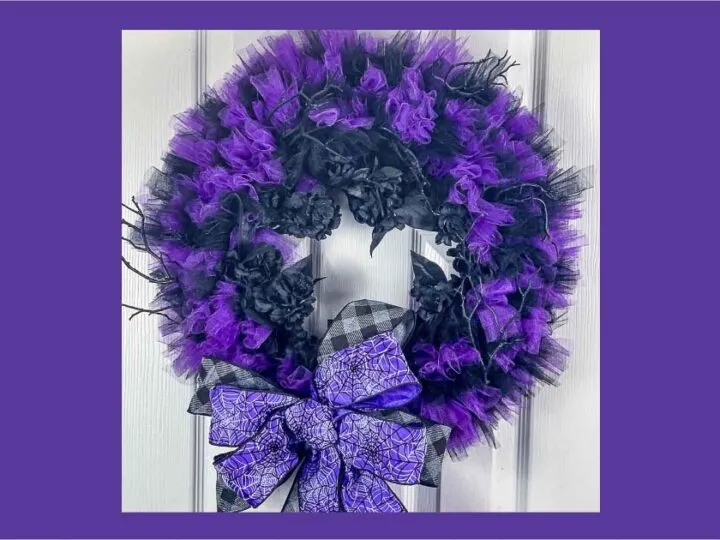 Black and purple tulle wreath with black flowers and a spider web bow