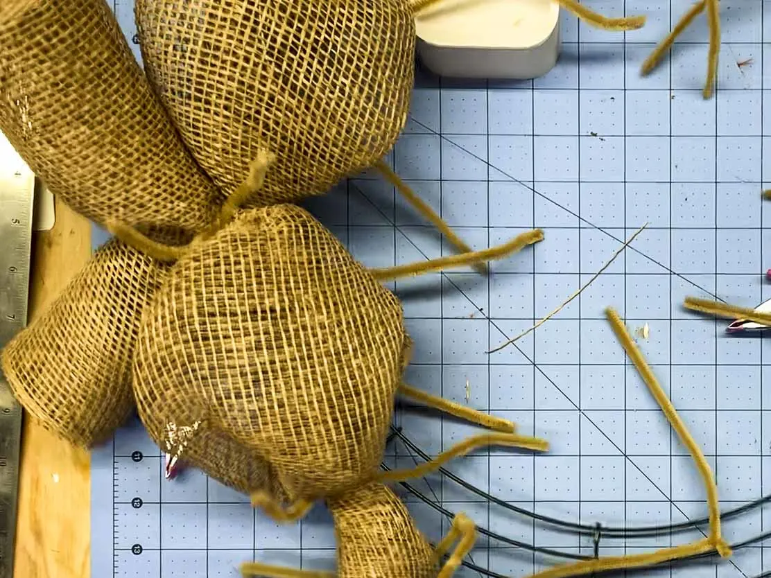 Pair of mesh curls crossed and attached to the same point on the wire wreath form using a single pipe cleaner