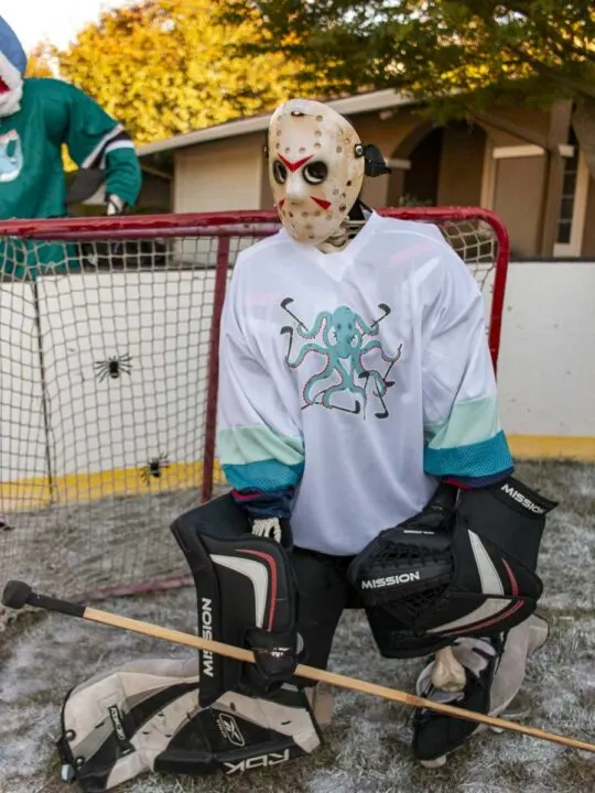 Skeleton hockey player wearing goalie gear, including a Friday the 13th Jason hockey mask. Jersey has an octopus with 8 hockey sticks.