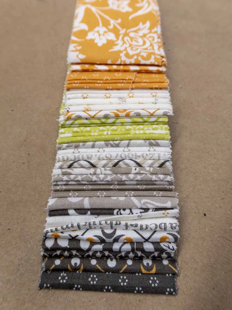Unrolled jelly roll consisting of 2.5" wide strips of fabric in a variety of coordinating colors and colors.
