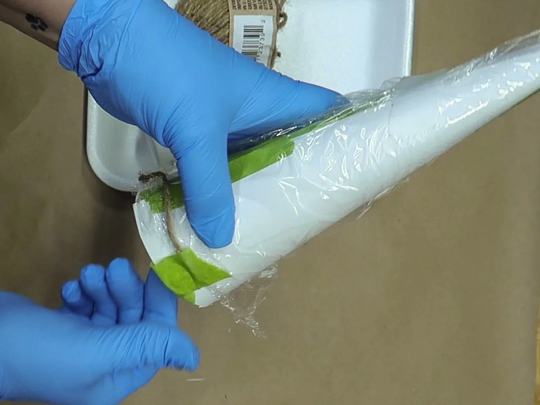 The starting piece of glue-covered twine taped to the bottom of the cone.