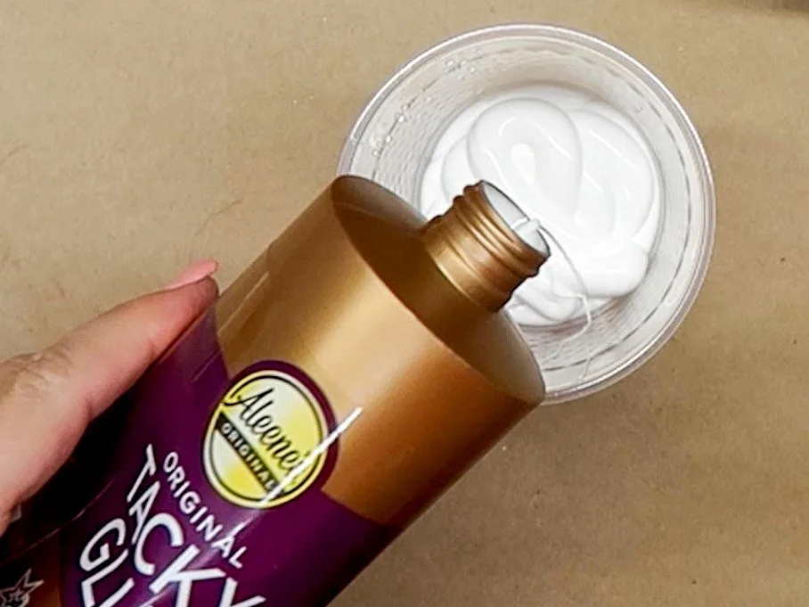 Pouring Aleene's Tacky Glue into a cup.
