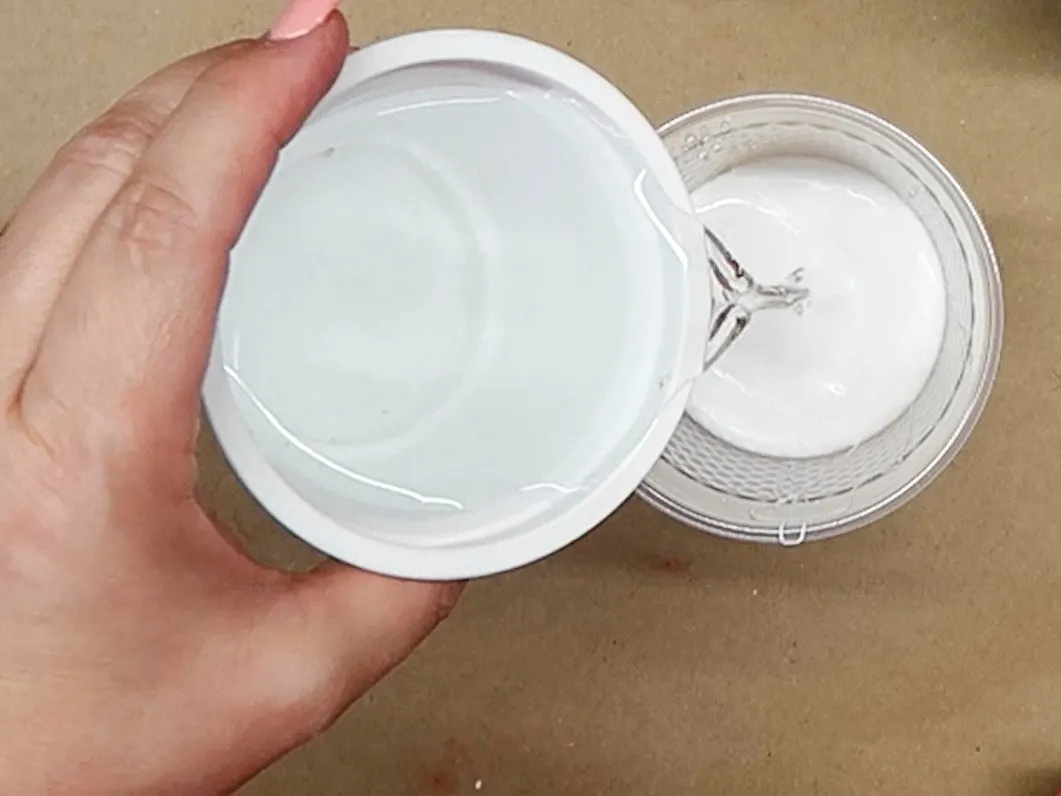 Pouring water into a cup that contains Aleene's Tacky Glue.