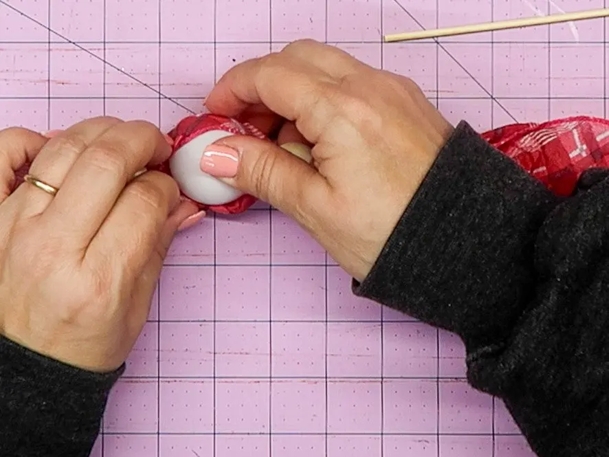 Hands putting the ball into the scarf pocket.